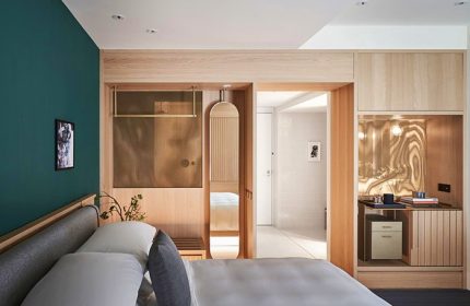 Kimpton Da An Hotel room. Modern, gay-friendly hotel design with wood accents, a green wall, and view into the bathroom. Ideal for gay travel.