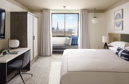 Kimpton Hotel Enso room. Gay-friendly hotel featuring a bed, desk, and window seat with a city view. Modern design and comfortable amenities.