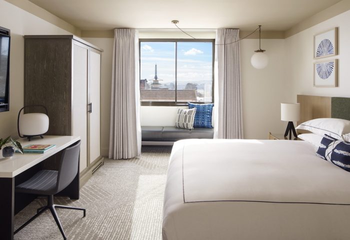Kimpton Hotel Enso room. Gay-friendly hotel featuring a bed, desk, and window seat with a city view. Modern design and comfortable amenities.