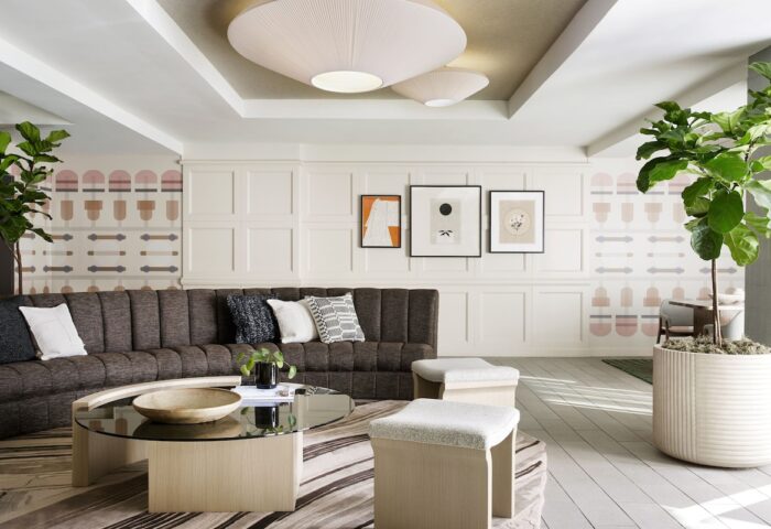 Kimpton Hotel Enso interior. Gay-friendly hotel lounge area with sofa, coffee table, stools, plants, and modern decor. Stylish, inviting space.