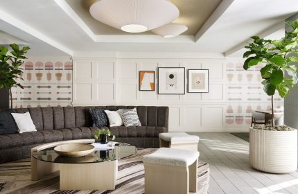 Kimpton Hotel Enso interior. Gay-friendly hotel lounge area with sofa, coffee table, stools, plants, and modern decor. Stylish, inviting space.