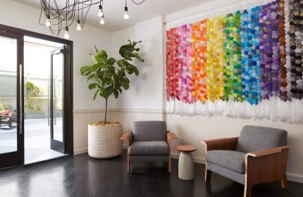 Kimpton Hotel Enso lobby with rainbow art, a gay-friendly hotel. Lounge area with chairs, plant, and modern design. Gay travel lodging.