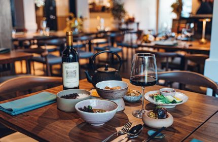 Kimpton Hotel Enso dining. Wine, teapot, & bowls of food on a wooden table. Gay-friendly hotel restaurant with a modern aesthetic.