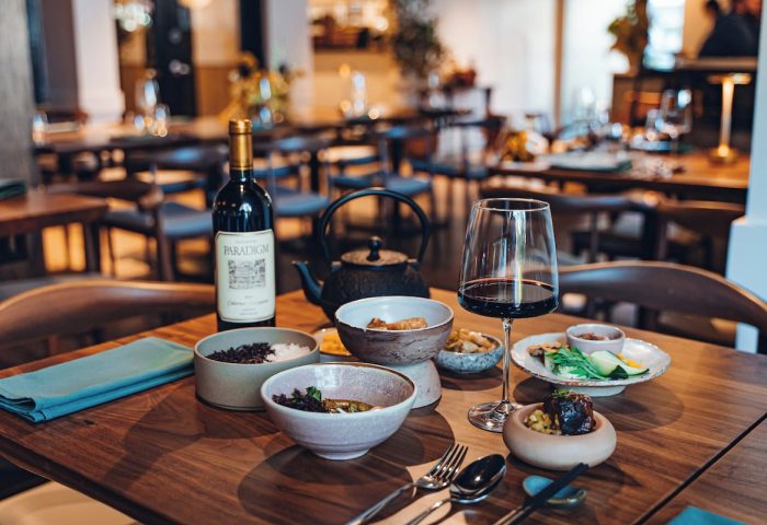 Kimpton Hotel Enso dining. Wine, teapot, & bowls of food on a wooden table. Gay-friendly hotel restaurant with a modern aesthetic.