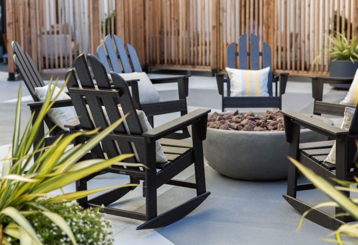 Kimpton Hotel Enso outdoor patio with rocking chairs around a fire pit. A gay-friendly hotel offering a welcoming space for relaxation.