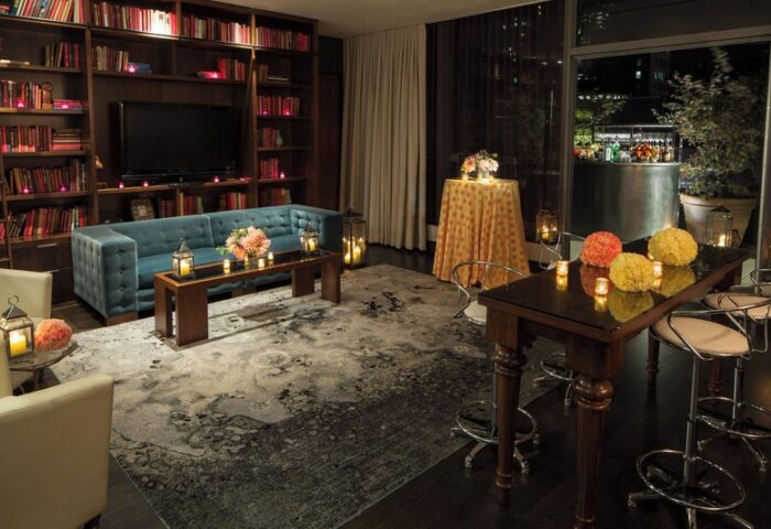 Kimpton Hotel Eventi gay-friendly hotel lounge. Bookshelves, sofa, and tables with flowers and candles create a warm, inviting atmosphere.