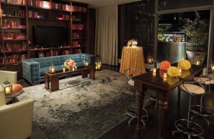 Kimpton Hotel Eventi gay-friendly hotel lounge. Bookshelves, sofa, and tables with flowers and candles create a warm, inviting atmosphere.