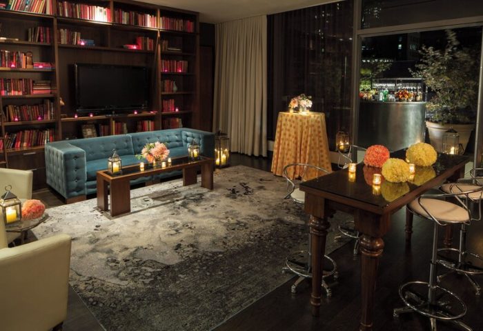 Kimpton Hotel Eventi gay-friendly hotel lounge. Bookshelves, sofa, and tables with flowers and candles create a warm, inviting atmosphere.