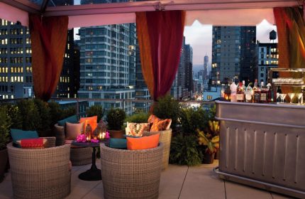 Kimpton Hotel Eventi rooftop bar with city views. Gay-friendly hotel with outdoor seating, drinks, and plants. Great spot for gay travelers.