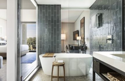 Kimpton Rowan Palm Springs Hotel bathroom. Bathtub, stool, and vanity. Gray tile. Gay-friendly hotel for gay men travelers.