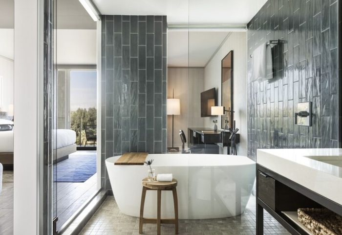 Kimpton Rowan Palm Springs Hotel bathroom. Bathtub, stool, and vanity. Gray tile. Gay-friendly hotel for gay men travelers.