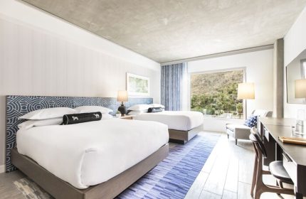 Kimpton Rowan Palm Springs Hotel room with two beds, blue accents, and mountain view. Gay-friendly hotel for gay travelers.