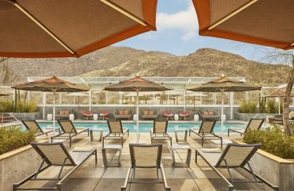 Kimpton Rowan Palm Springs Hotel pool view. Gay-friendly hotel with lounge chairs and umbrellas. Desert mountains in the background.