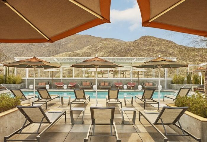 Kimpton Rowan Palm Springs Hotel pool view. Gay-friendly hotel with lounge chairs and umbrellas. Desert mountains in the background.