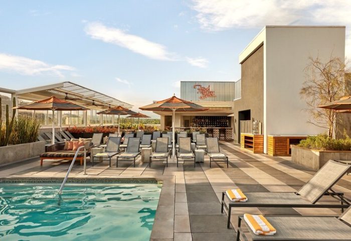 Rooftop pool and bar at Kimpton Rowan Palm Springs Hotel. Gay-friendly hotel with lounge chairs, umbrellas, and a stylish bar area. Palm Springs travel.