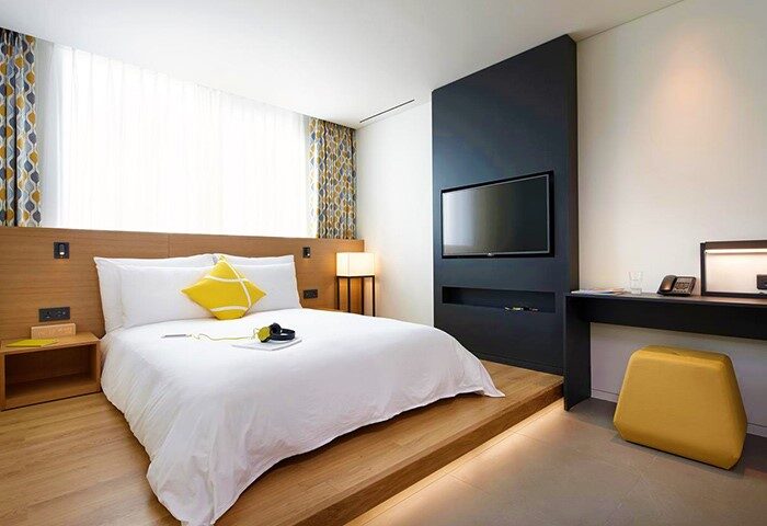 L7 Myeongdong by LOTTE hotel room. Modern design, platform bed, yellow accents. A stylish, gay-friendly hotel choice in Seoul, South Korea.