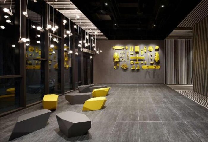 Lobby of L7 Myeongdong by LOTTE, a gay-friendly hotel. Modern design with yellow accents, geometric benches, and unique wall art. Stylish interior.