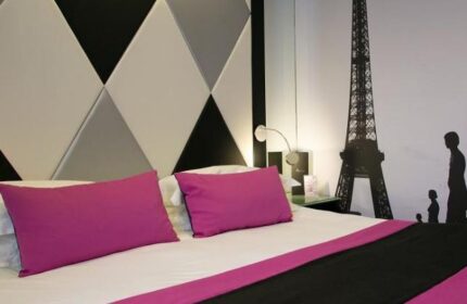 L'Empire Paris Hotel room with Eiffel Tower wall art. Gay-friendly, pet-friendly hotel interior with modern design and pink pillows.