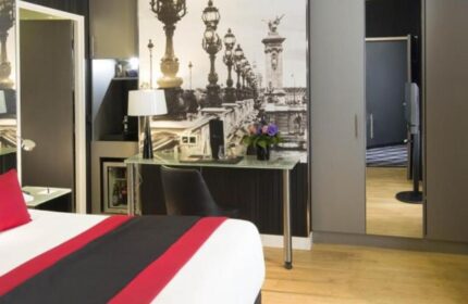L'Empire Paris Hotel room. Gay-friendly, pet-friendly hotel. Room features a bed, desk, and a Paris-themed wall decoration.