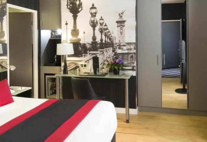 L'Empire Paris Hotel room. Gay-friendly, pet-friendly hotel. Room features a bed, desk, and a Paris-themed wall decoration.