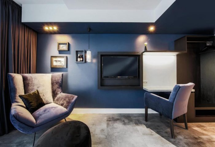Lindemanns Hotel room with blue walls, TV, and comfortable chairs. Gay-friendly hotel in Berlin, Germany. Modern design, perfect for gay travelers.