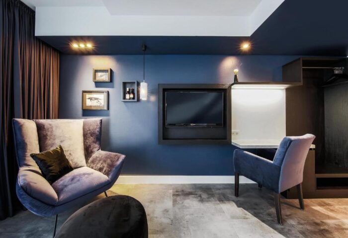 Lindemanns Hotel room with blue walls, TV, and comfortable chairs. Gay-friendly hotel in Berlin, Germany. Modern design, perfect for gay travelers.