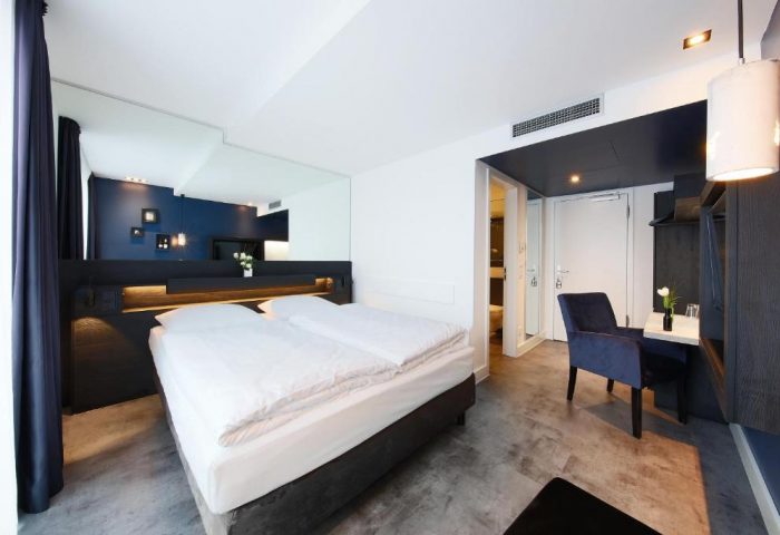 Lindemann's Hotel room. Gay-friendly hotel with modern decor, double bed, blue accent wall, and sleek furniture. Ideal for gay travel in Berlin.