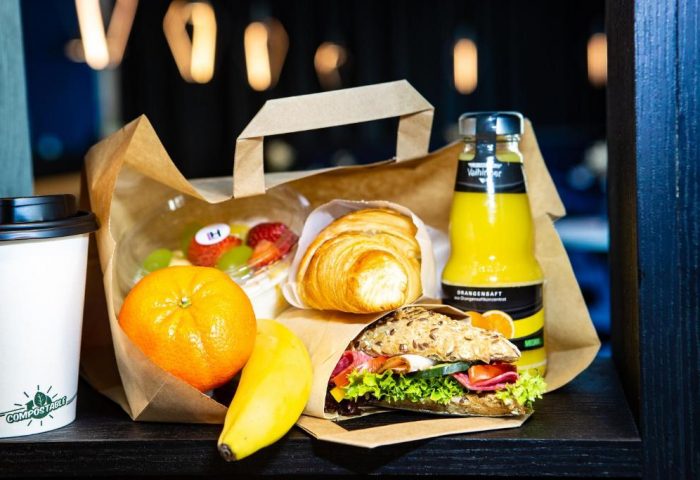 Lindemann's Hotel breakfast: pastry, sandwich, fruit, juice, coffee in a bag. Gay-friendly hotel serving fresh food. Travel advice for gay men.