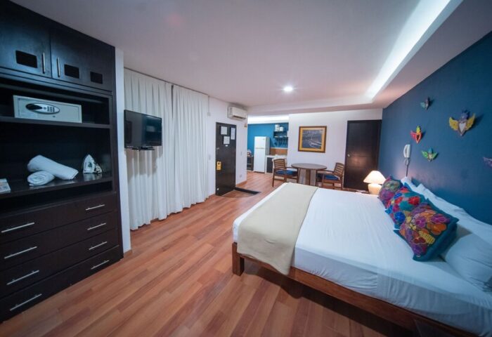 La Iguana Vallarta LGBT adults-only hotel room in Romantic Zone. Bed, kitchenette, blue wall with art, closet with safe. Party, clubbing.