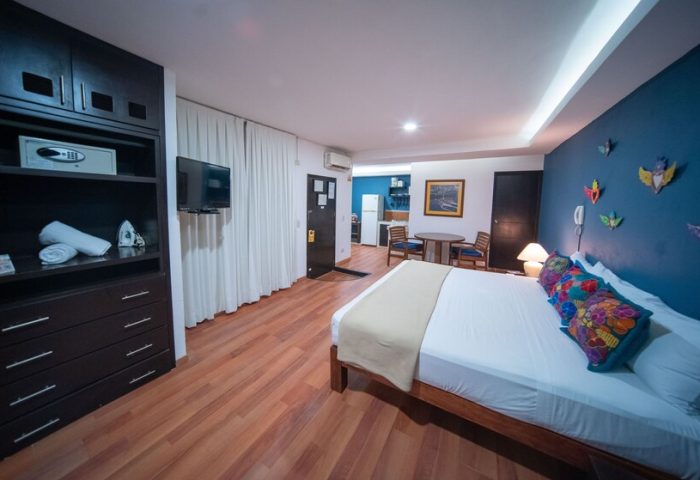 La Iguana Vallarta LGBT adults-only hotel room in Romantic Zone. Bed, kitchenette, blue wall with art, closet with safe. Party, clubbing.
