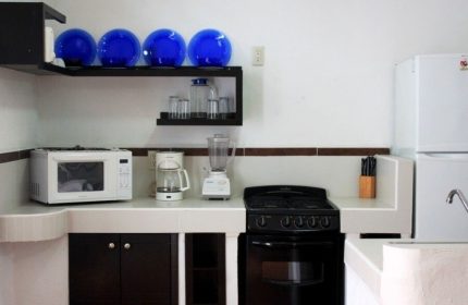 La Iguana Vallarta LGBT adults-only hotel kitchenette. Microwave, stove, fridge, blender, and blue decorative glass bowls. Romantic Zone.