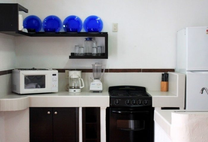 La Iguana Vallarta LGBT adults-only hotel kitchenette. Microwave, stove, fridge, blender, and blue decorative glass bowls. Romantic Zone.