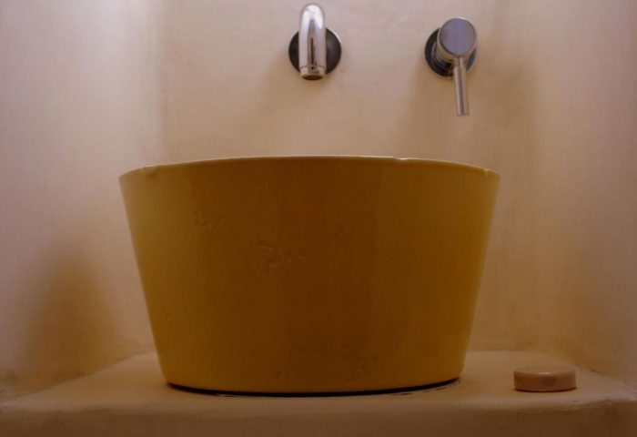 La Maison Kalogera gay-friendly hotel sink. Unique yellow basin with chrome fixtures. Modern bathroom design for gay men travelers.
