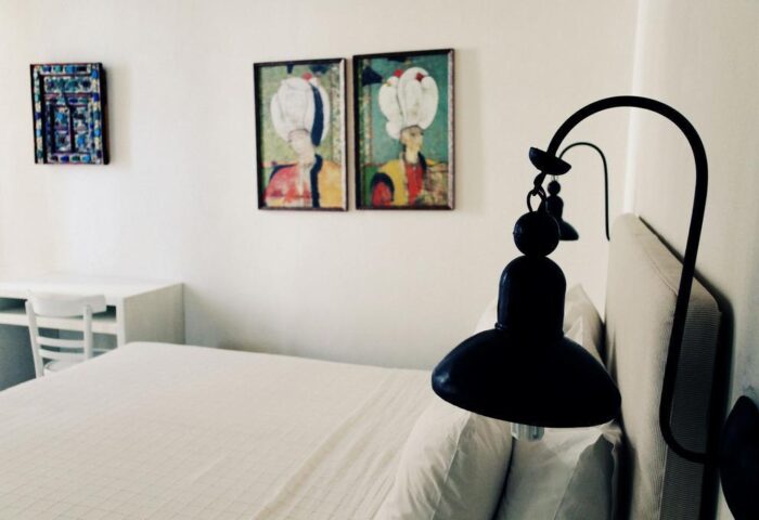 La Maison Kalogera gay-friendly hotel room. Bed with white linens, black lamp, and wall art. Modern, clean design for gay travelers.