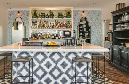 Bar at La Serena Villas, a gay-friendly Kirkwood Collection Hotel. Stylish interior with patterned tiles and fully stocked shelves.