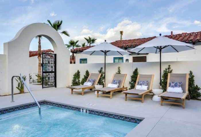 Poolside at La Serena Villas, a gay-friendly hotel. Loungers with umbrellas offer relaxation. Kirkwood Collection Hotel provides luxury travel.