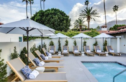 Poolside view at La Serena Villas, a gay-friendly Kirkwood Collection Hotel. Lounge chairs, umbrellas, and palm trees create a relaxing oasis.