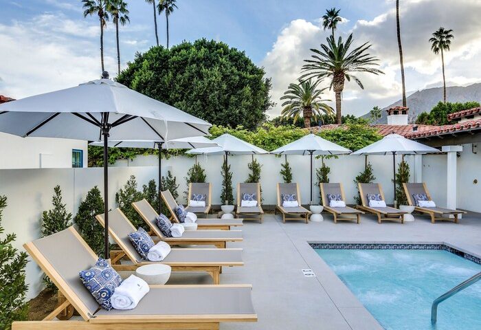 Poolside view at La Serena Villas, a gay-friendly Kirkwood Collection Hotel. Lounge chairs, umbrellas, and palm trees create a relaxing oasis.