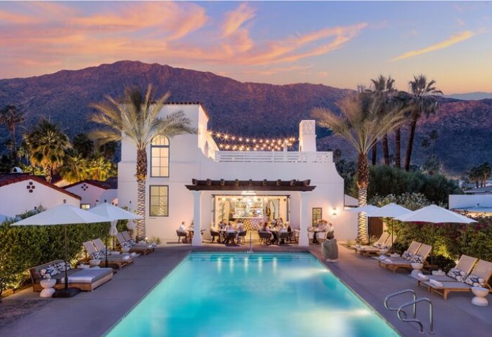 La Serena Villas, A Kirkwood Collection Hotel pool view at dusk. Gay-friendly hotel with bar, lounge chairs, and mountain backdrop. Palm Springs.
