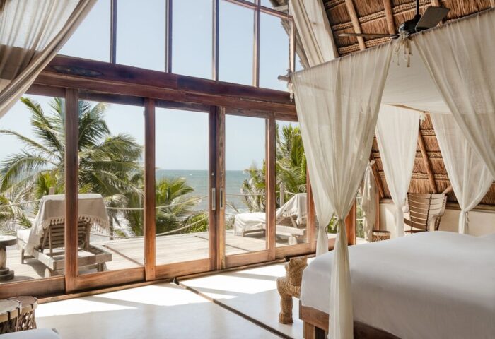 La Valise Tulum gay-friendly hotel room. Ocean view from a suite with a four-poster bed and deck chairs. Tropical gay travel.