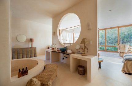 La Valise Tulum gay-friendly hotel bathroom. Features a round mirror, soaking tub, and natural light. Perfect for gay travel in Tulum.
