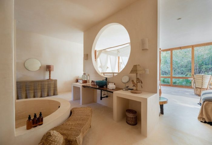 La Valise Tulum gay-friendly hotel bathroom. Features a round mirror, soaking tub, and natural light. Perfect for gay travel in Tulum.