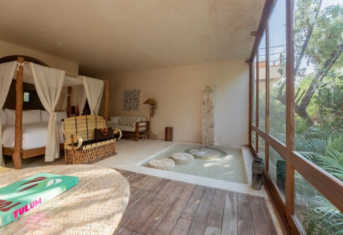 La Valise Tulum gay-friendly hotel room. Canopy bed, indoor fountain, & rustic decor create a luxurious, relaxing vibe. Perfect for gay travel.