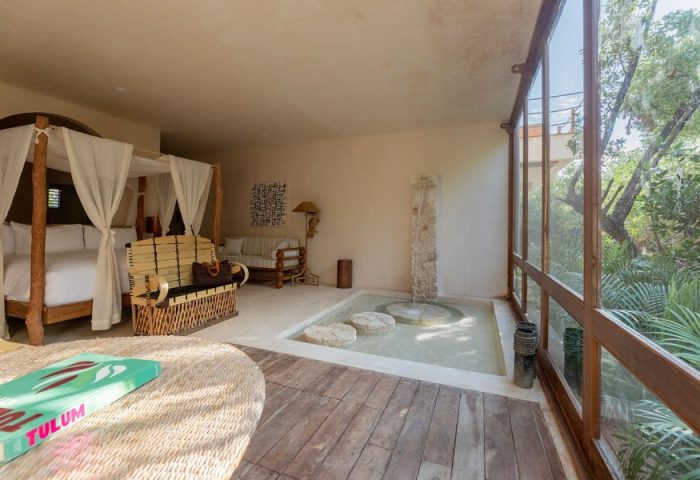 La Valise Tulum gay-friendly hotel room. Canopy bed, indoor fountain, & rustic decor create a luxurious, relaxing vibe. Perfect for gay travel.