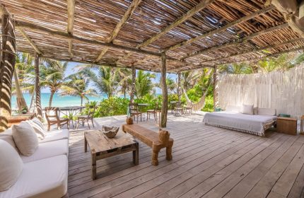 La Valise Tulum gay-friendly hotel patio. Beachfront view, wooden deck with seating, bed, and hammock. Tropical getaway for gay men.