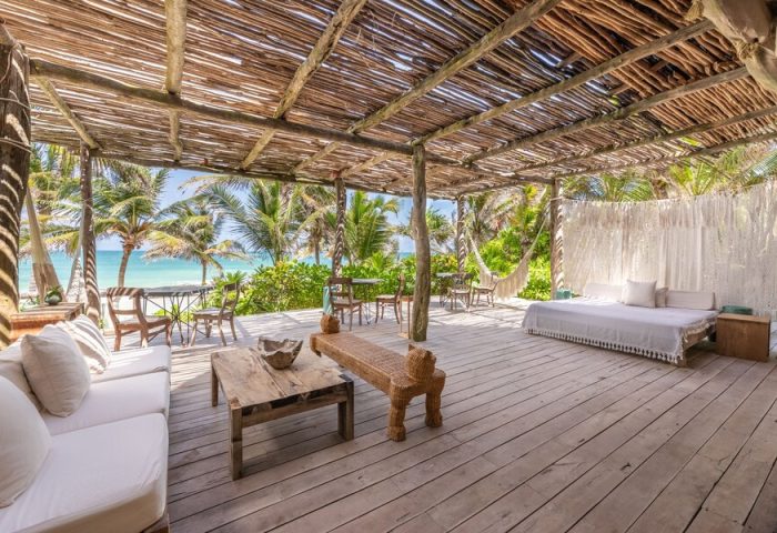 La Valise Tulum gay-friendly hotel patio. Beachfront view, wooden deck with seating, bed, and hammock. Tropical getaway for gay men.