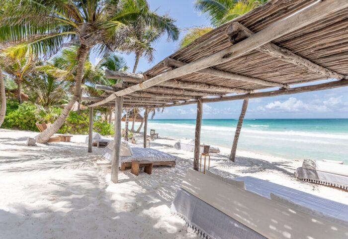 La Valise Tulum gay-friendly hotel beach view. Thatched roof, palm trees, and ocean scene. Ideal for gay men's travel in Tulum, Mexico.