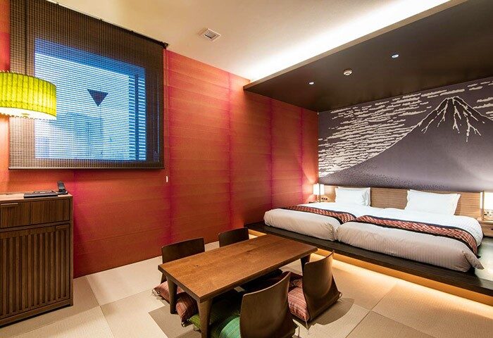 La'gent Hotel Shinjuku Kabukicho room. Gay-friendly hotel with twin beds, Japanese table, and Mount Fuji mural. Modern design.