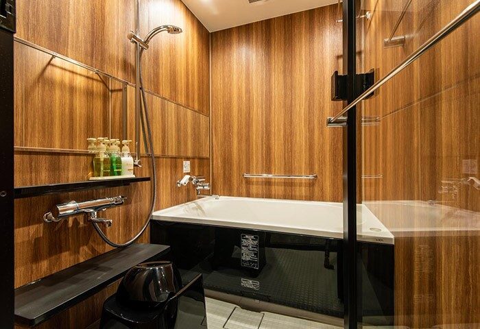 L'gent Hotel Shinjuku Kabukicho bathroom. Wood paneled walls, shower, and soaking tub. Gay-friendly hotel in Tokyo's entertainment district.