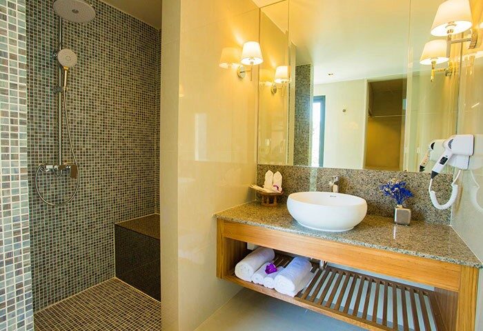 Bathroom at Lanna Thaphae Hotel, a gay-friendly hotel. Features a shower, sink, granite countertop, towels, and hairdryer for gay men travelers.